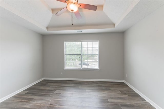 empty room with a tray ceiling, ceiling fan, and hardwood / wood-style flooring