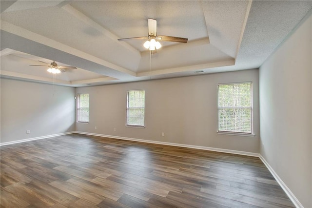 spare room featuring ceiling fan, wood-type flooring, a textured ceiling, and a tray ceiling