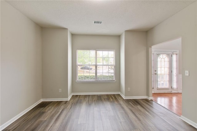 unfurnished room with a textured ceiling and hardwood / wood-style flooring