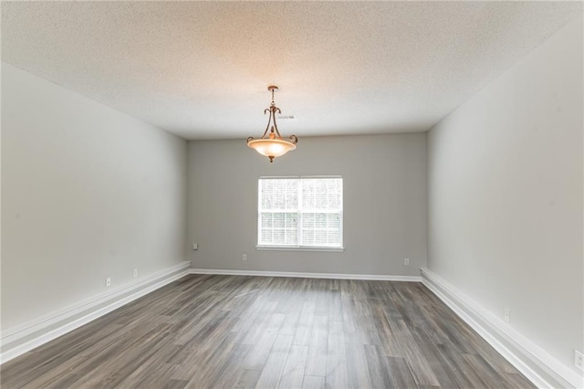 unfurnished room with dark hardwood / wood-style floors and a textured ceiling