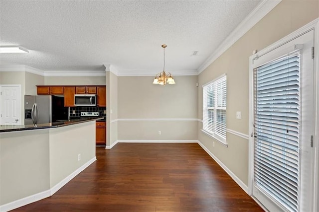 kitchen featuring appliances with stainless steel finishes, hanging light fixtures, dark hardwood / wood-style floors, a notable chandelier, and ornamental molding