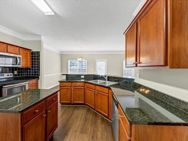 kitchen featuring appliances with stainless steel finishes, dark hardwood / wood-style floors, pendant lighting, sink, and kitchen peninsula