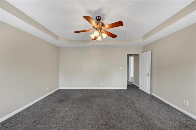 carpeted spare room featuring a textured ceiling, ceiling fan, and a tray ceiling