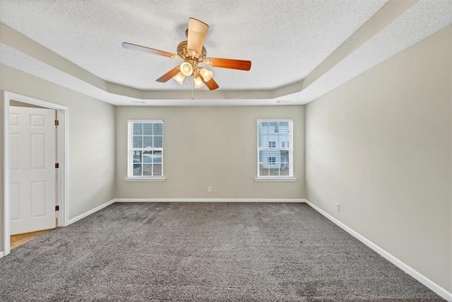 carpeted spare room featuring ceiling fan, a textured ceiling, and a tray ceiling