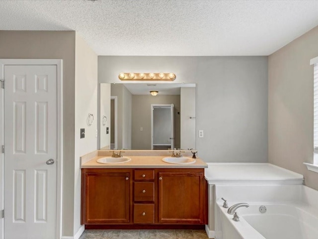 bathroom featuring vanity, a textured ceiling, and a bathtub