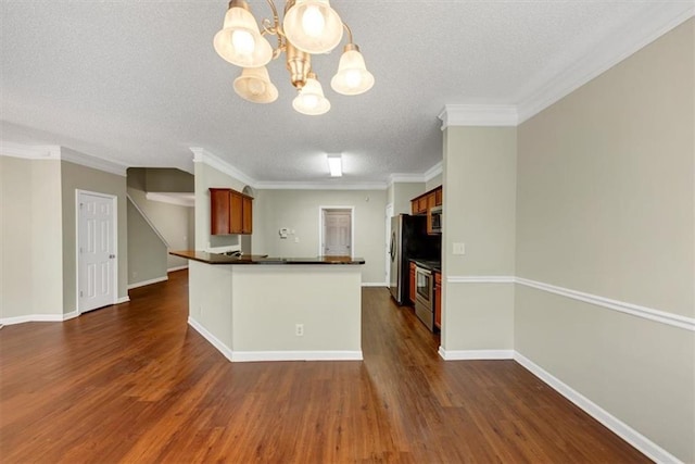 kitchen with dark wood-type flooring, hanging light fixtures, stainless steel appliances, a notable chandelier, and a textured ceiling