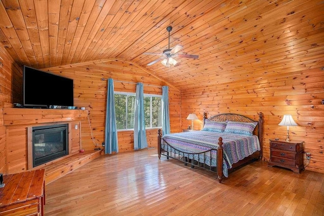 bedroom with lofted ceiling, wood walls, wooden ceiling, access to outside, and hardwood / wood-style floors