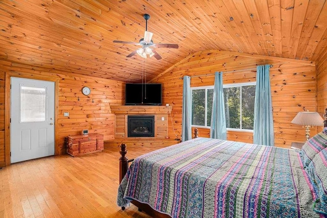 bedroom featuring vaulted ceiling, light hardwood / wood-style floors, wood ceiling, and wood walls