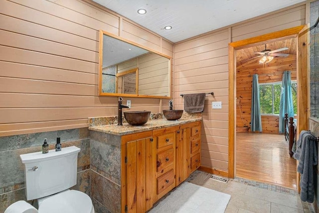 bathroom with vanity, wood walls, ceiling fan, and toilet