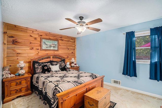 carpeted bedroom featuring ceiling fan, a textured ceiling, and wooden walls