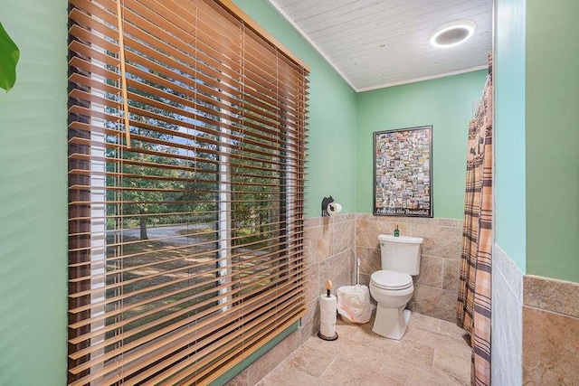 bathroom with crown molding, tile walls, and toilet