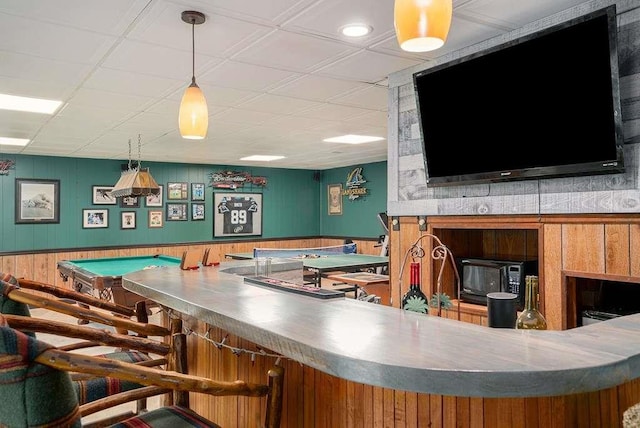 bar featuring hanging light fixtures and wood walls