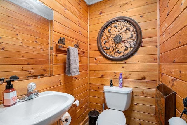 bathroom with sink, wood walls, and toilet