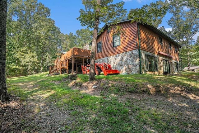 view of side of home with a wooden deck and a lawn