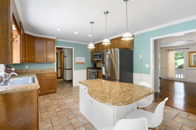 kitchen with a center island, sink, hanging light fixtures, ornamental molding, and stainless steel appliances