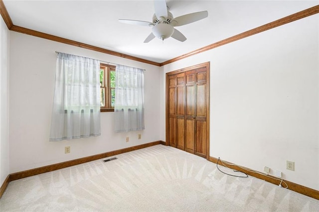 unfurnished bedroom with ceiling fan, ornamental molding, light carpet, and a closet