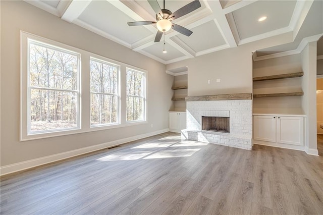 unfurnished living room featuring light wood-type flooring, a brick fireplace, a healthy amount of sunlight, and coffered ceiling