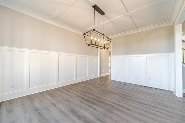 unfurnished dining area with wood-type flooring, an inviting chandelier, and crown molding