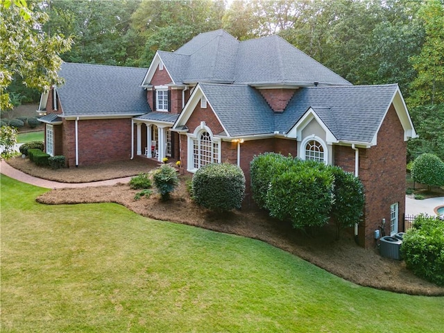 traditional-style house featuring brick siding, roof with shingles, and a front yard