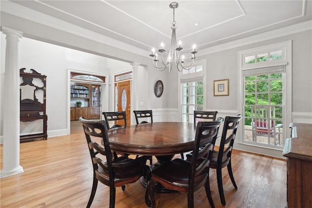 dining room featuring light wood-style flooring, crown molding, and decorative columns