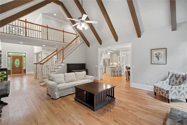 living area featuring beam ceiling, high vaulted ceiling, stairs, and light wood-style floors