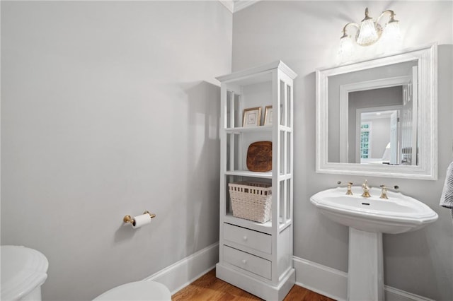 half bath featuring toilet, baseboards, and wood finished floors