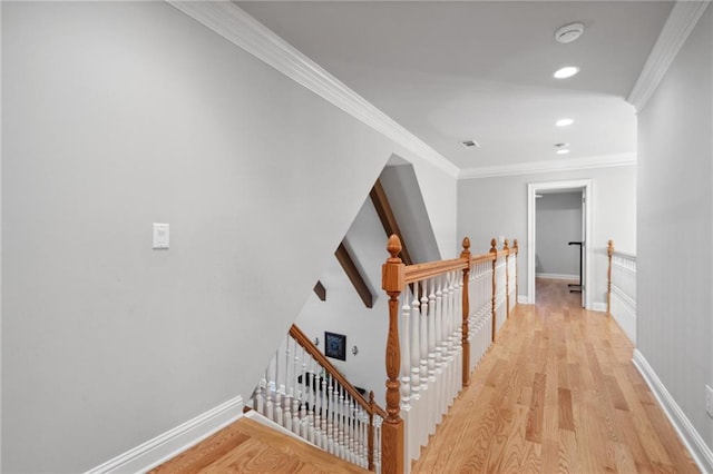 corridor with crown molding, baseboards, light wood-type flooring, an upstairs landing, and recessed lighting