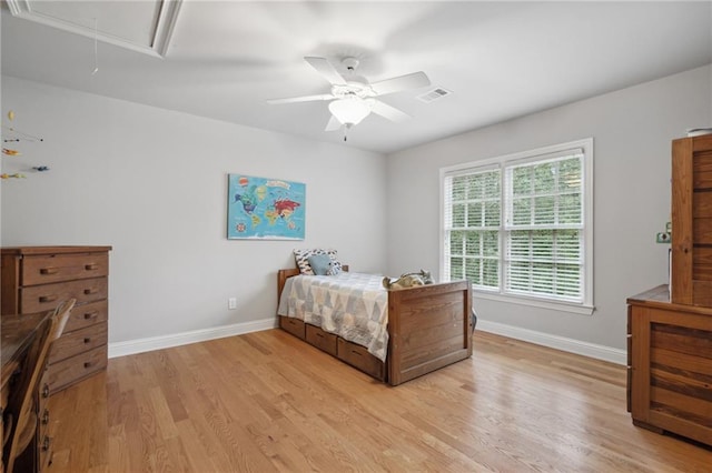 bedroom with a ceiling fan, baseboards, visible vents, light wood finished floors, and attic access