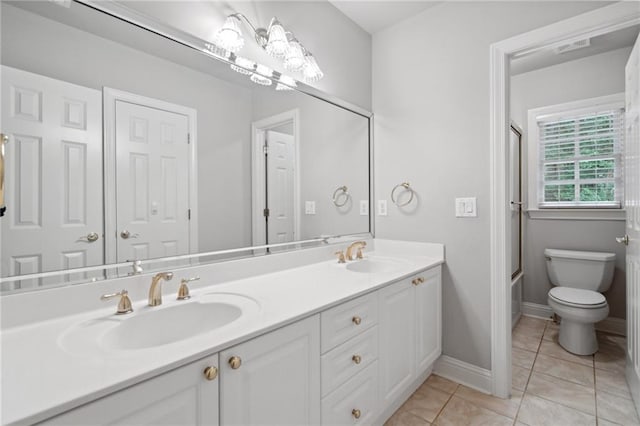 bathroom with double vanity, tile patterned floors, toilet, and a sink