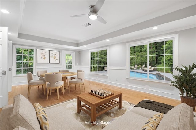 living room featuring visible vents, crown molding, a decorative wall, and wood finished floors