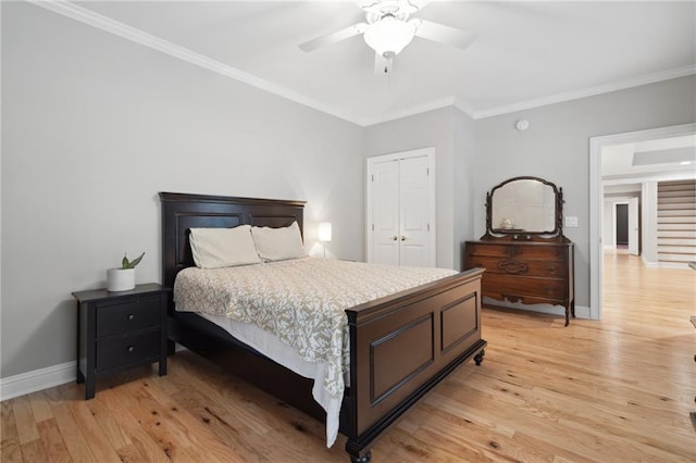 bedroom with a closet, baseboards, crown molding, and light wood finished floors