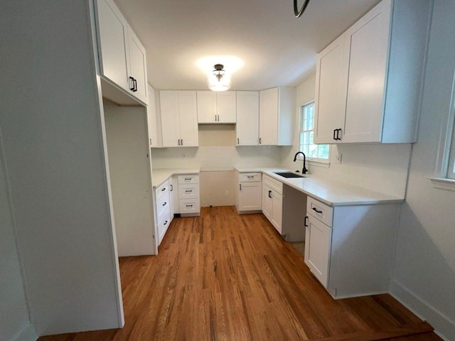 kitchen with light hardwood / wood-style floors, sink, and white cabinetry