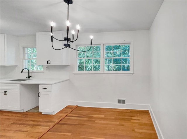 kitchen with plenty of natural light, sink, light hardwood / wood-style flooring, and white cabinets