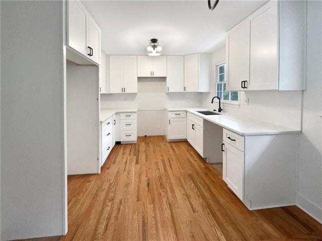 kitchen featuring white cabinets, light wood-type flooring, and sink