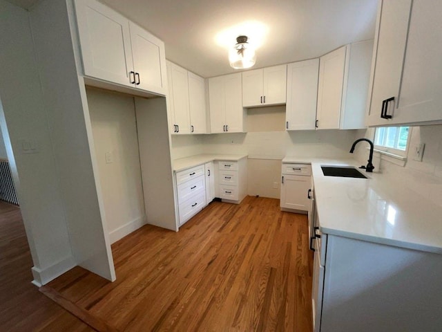 kitchen with white cabinets, sink, and light hardwood / wood-style floors