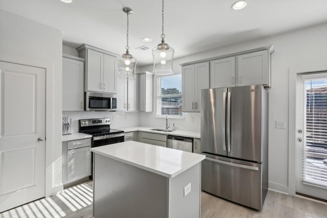 kitchen with stainless steel appliances, sink, decorative light fixtures, a center island, and gray cabinets