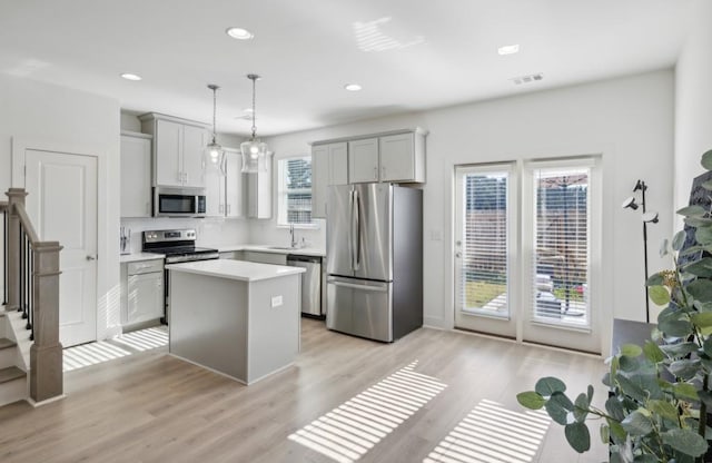 kitchen featuring pendant lighting, a kitchen island, a healthy amount of sunlight, and stainless steel appliances