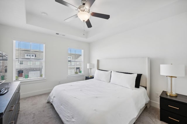 bedroom featuring ceiling fan, light carpet, and multiple windows