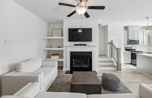 living room with ceiling fan and light hardwood / wood-style flooring