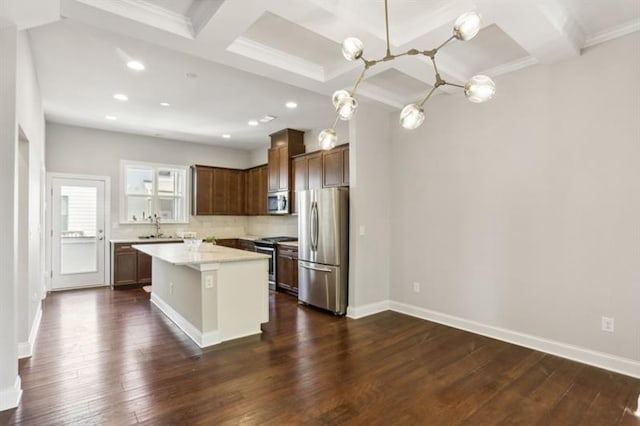 kitchen featuring dark wood-style flooring, coffered ceiling, light countertops, appliances with stainless steel finishes, and a center island