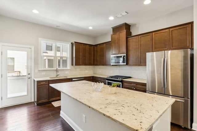 kitchen with a center island, visible vents, appliances with stainless steel finishes, a sink, and light stone countertops