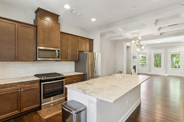 kitchen featuring dark wood-type flooring, coffered ceiling, a kitchen island, appliances with stainless steel finishes, and decorative backsplash