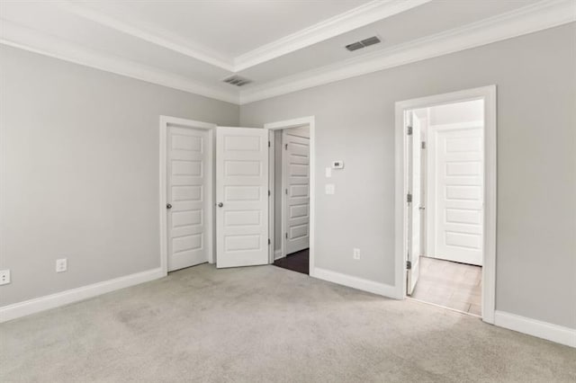 unfurnished bedroom featuring ornamental molding, a tray ceiling, carpet flooring, and baseboards