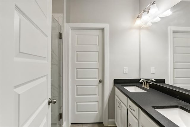 bathroom with double vanity, a shower with door, and a sink