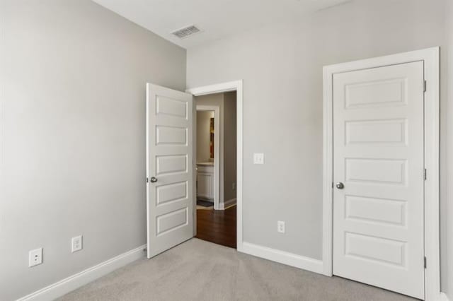 unfurnished bedroom with light colored carpet, visible vents, and baseboards