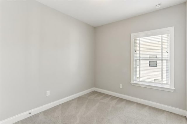 unfurnished room with light carpet and baseboards