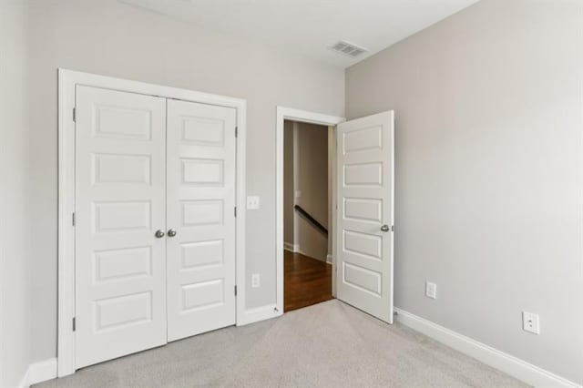 unfurnished bedroom with light colored carpet, a closet, visible vents, and baseboards