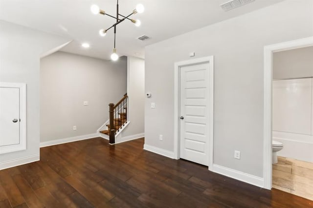 basement with baseboards, visible vents, stairway, and dark wood-type flooring