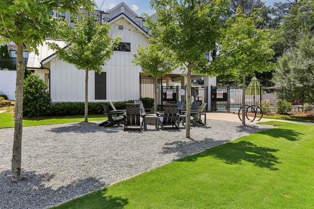 view of property's community featuring a lawn, a patio area, and fence