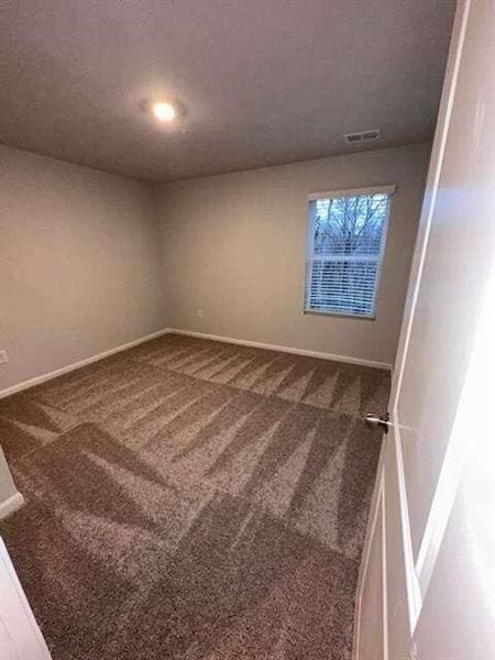 empty room featuring visible vents, carpet floors, and baseboards